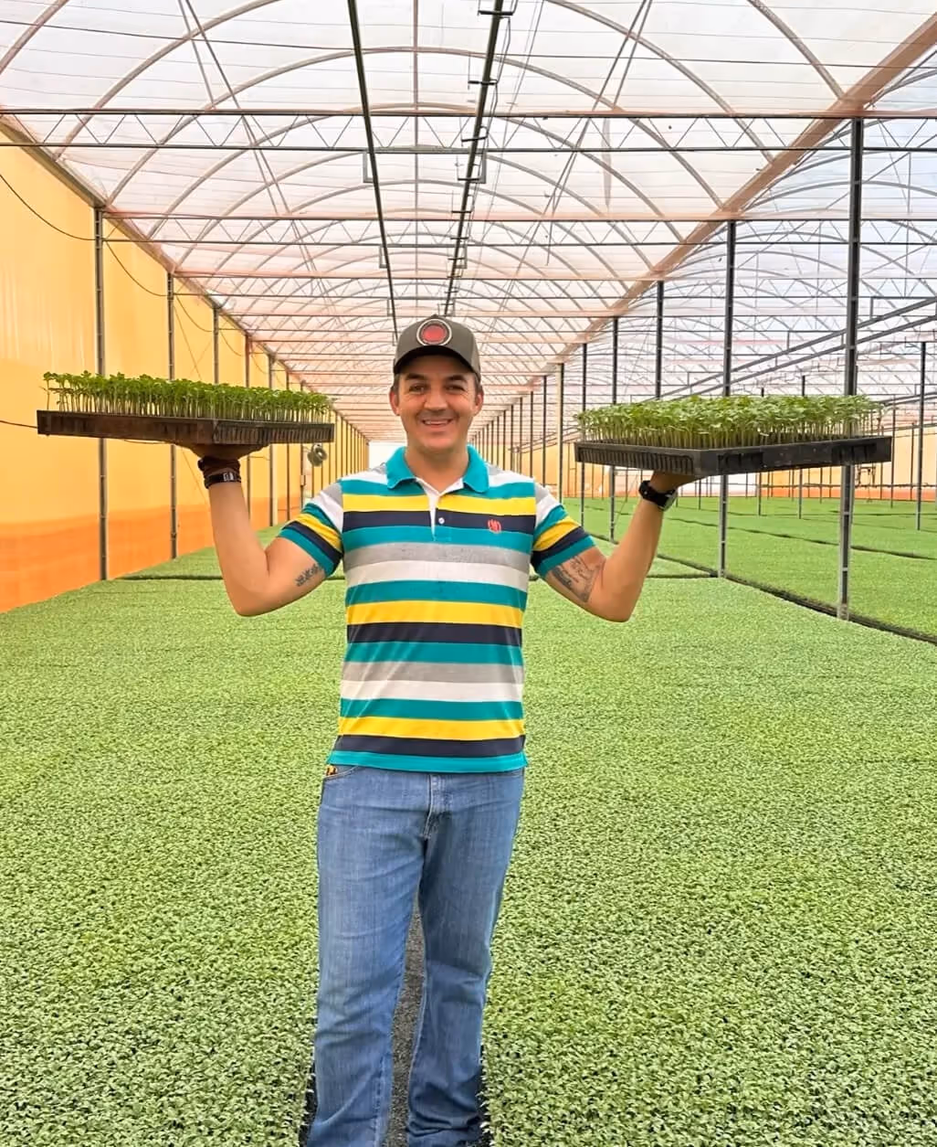 Lucas Siqueira no viveiro com bandejas de mudas